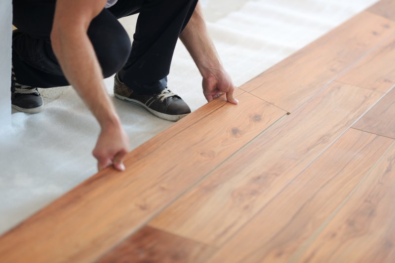 a contractor laying wood flooring in a person’s home