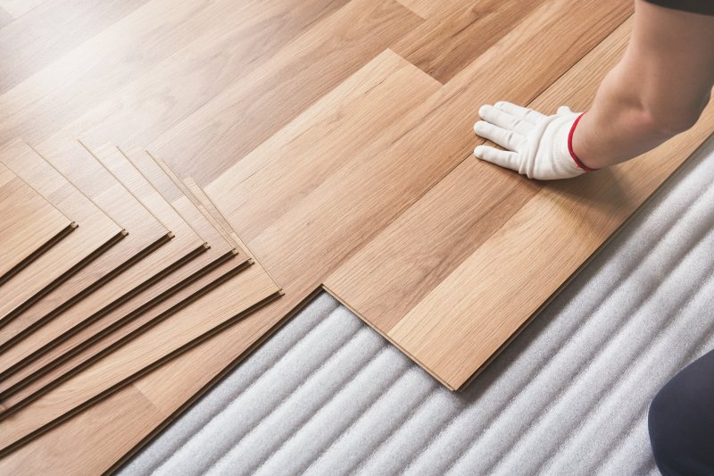 a professional laying laminate flooring in a person’s home