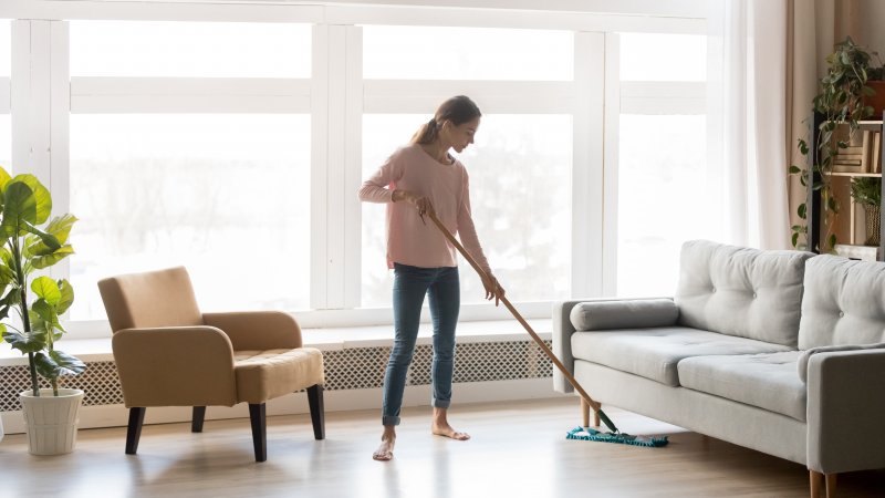 a woman using a dust mop to clean her floors