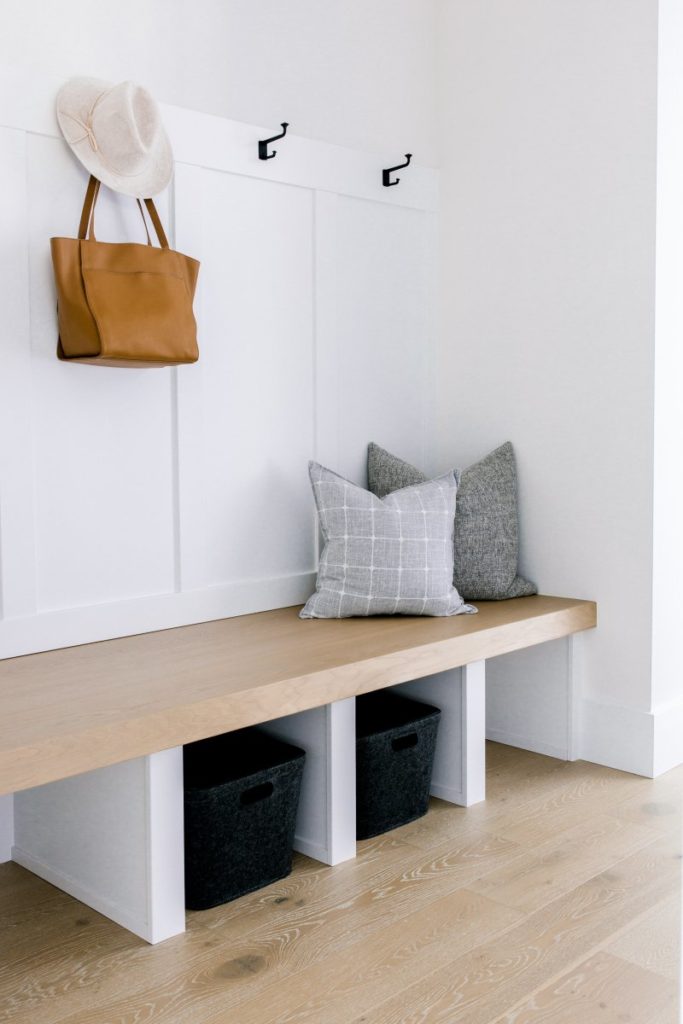 a bare mudroom with only a few pillows and a purse and hat