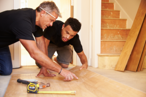 two men laying hardwood floors in a house