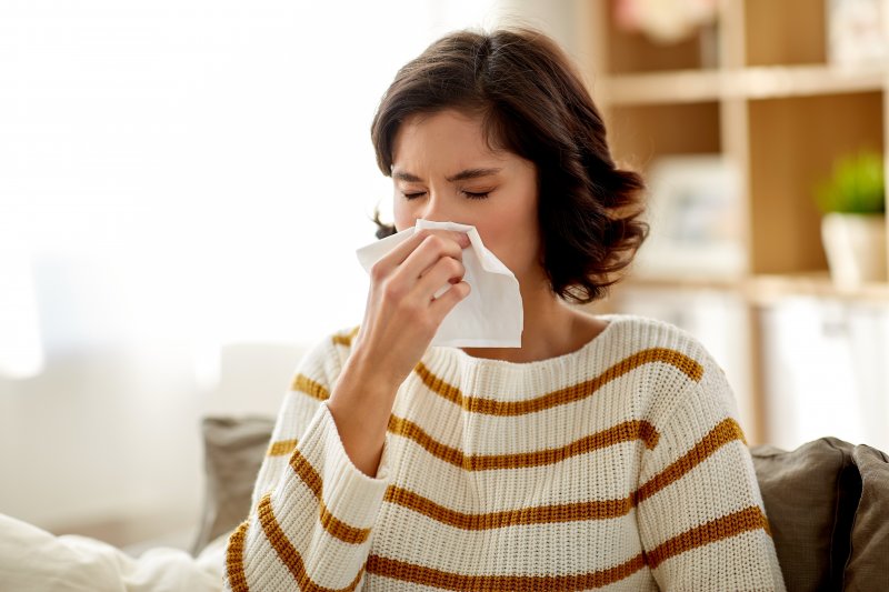 woman blowing her nose because of allergies